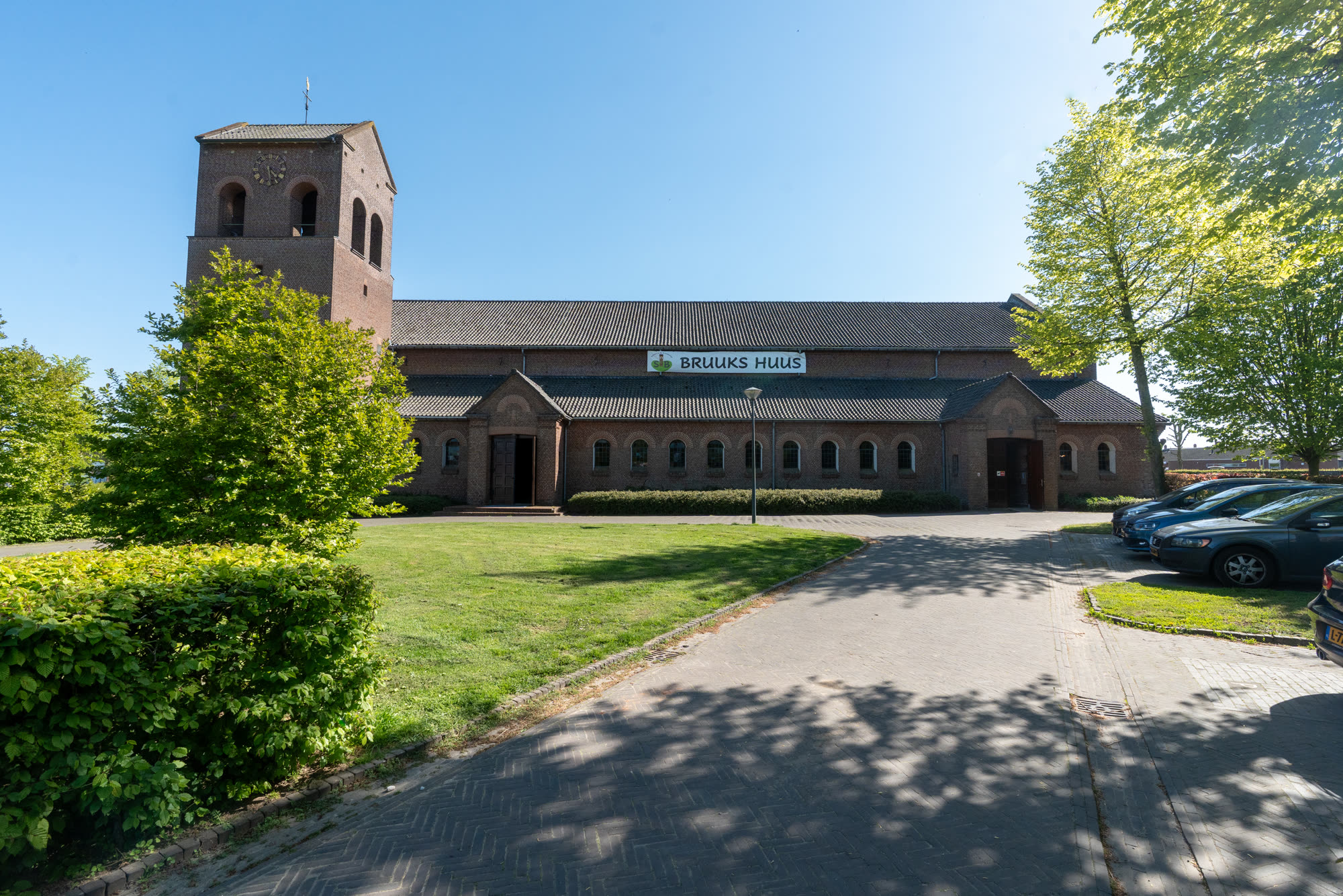 Bruuks Huus in het zonlicht, met het spandoek Bruuks Huus en een geslingerd klinkerpad.